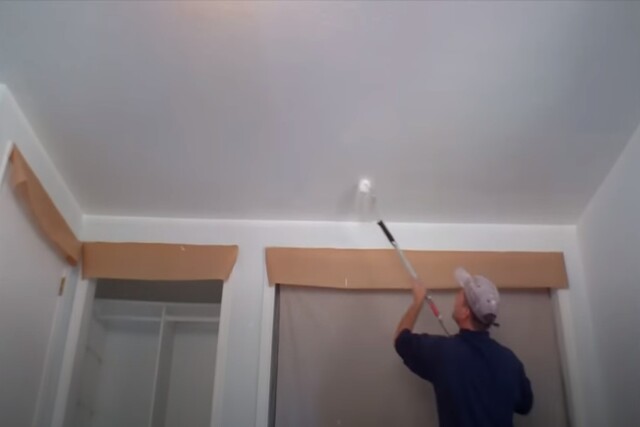 Worker performing interior painting of a ceiling